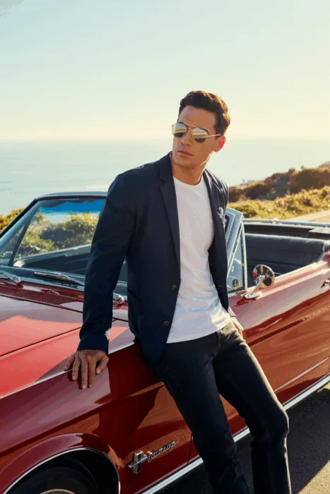 WordPress Alt Text:
Stylish outfit ideas men cars: man in sunglasses, navy blazer, and jeans leaning on a red convertible at the seaside, casual yet sharp fashion look.