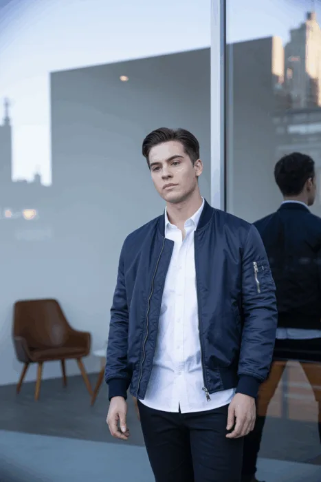 Stylish selfie poses men: young man in navy jacket and white shirt posing confidently in front of glass building.