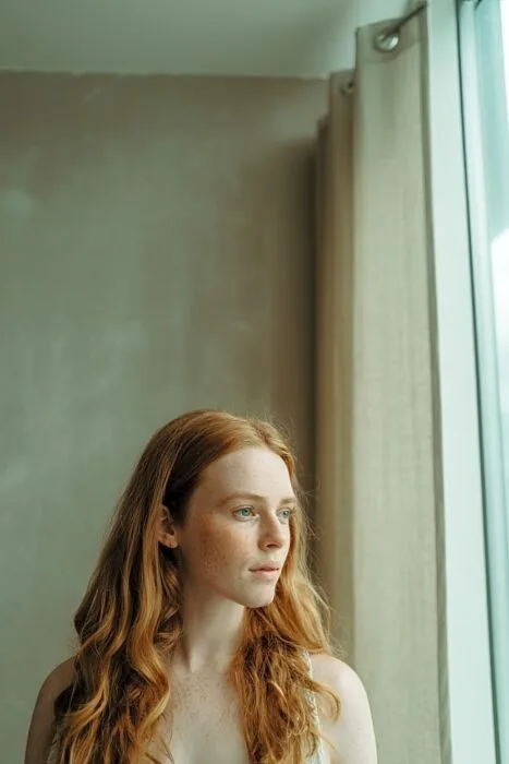 Woman standing near a window demonstrating natural light for birthday photos.