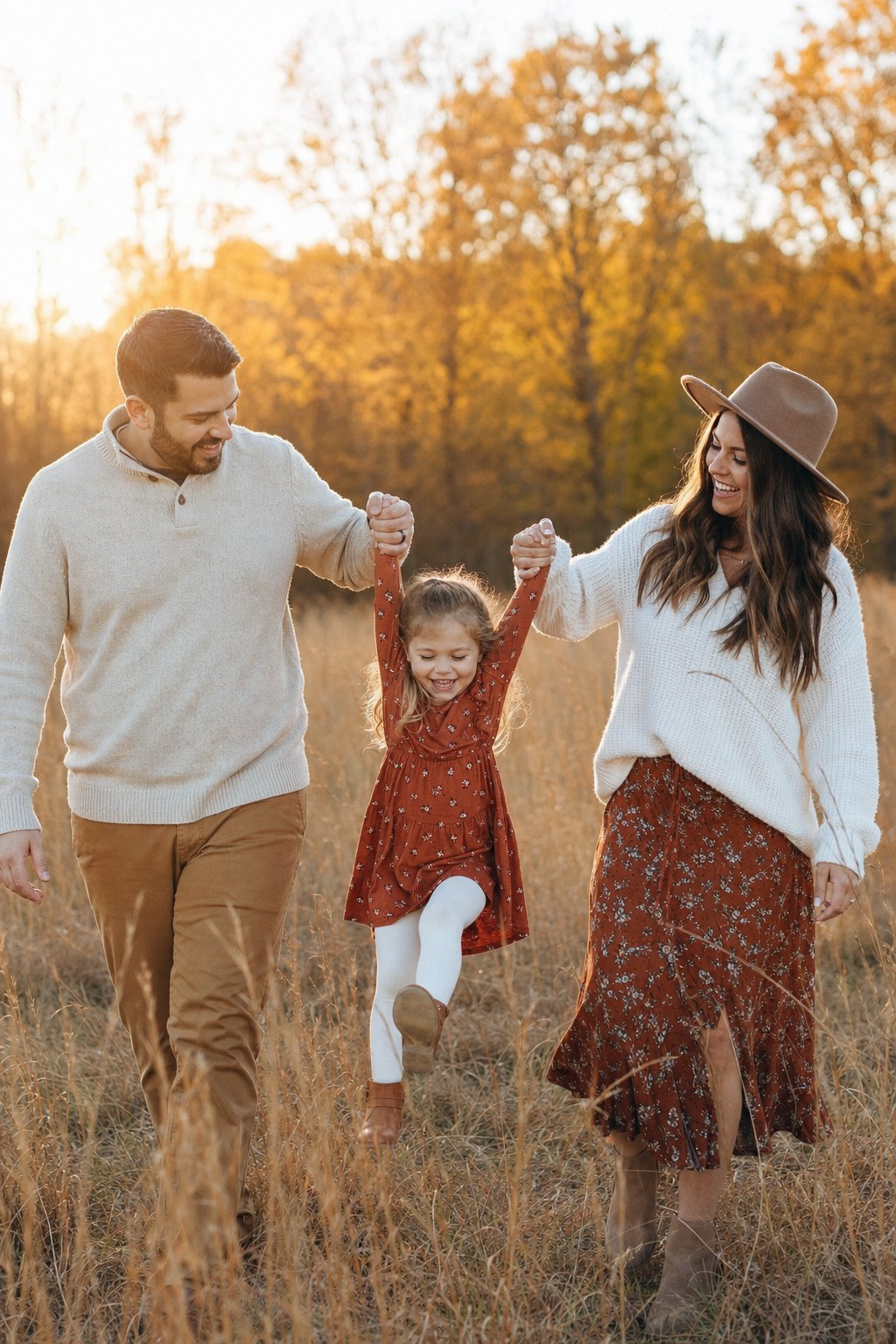 Family of 3 outdoor photo &mdash; parents swinging child through golden autumn field